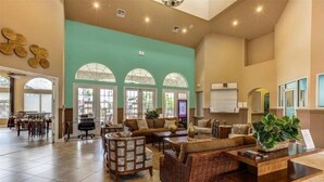 A spacious lobby with a large seating area, a reception desk, and a view of the outside through arched windows. - 5 Suites - Game Room Theater Room Private Pool (Kissimmee)