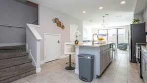 A modern kitchen with a central island, built-in appliances, and a staircase leading to another level. - Beautiful 4 Bed 3 5 Bath With Jacuzzi (Kissimmee)