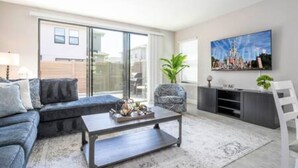 A modern living room with a sofa, coffee table, and a TV on the wall. - Beautiful 4 Bed 3 5 Bath With Jacuzzi (Kissimmee)