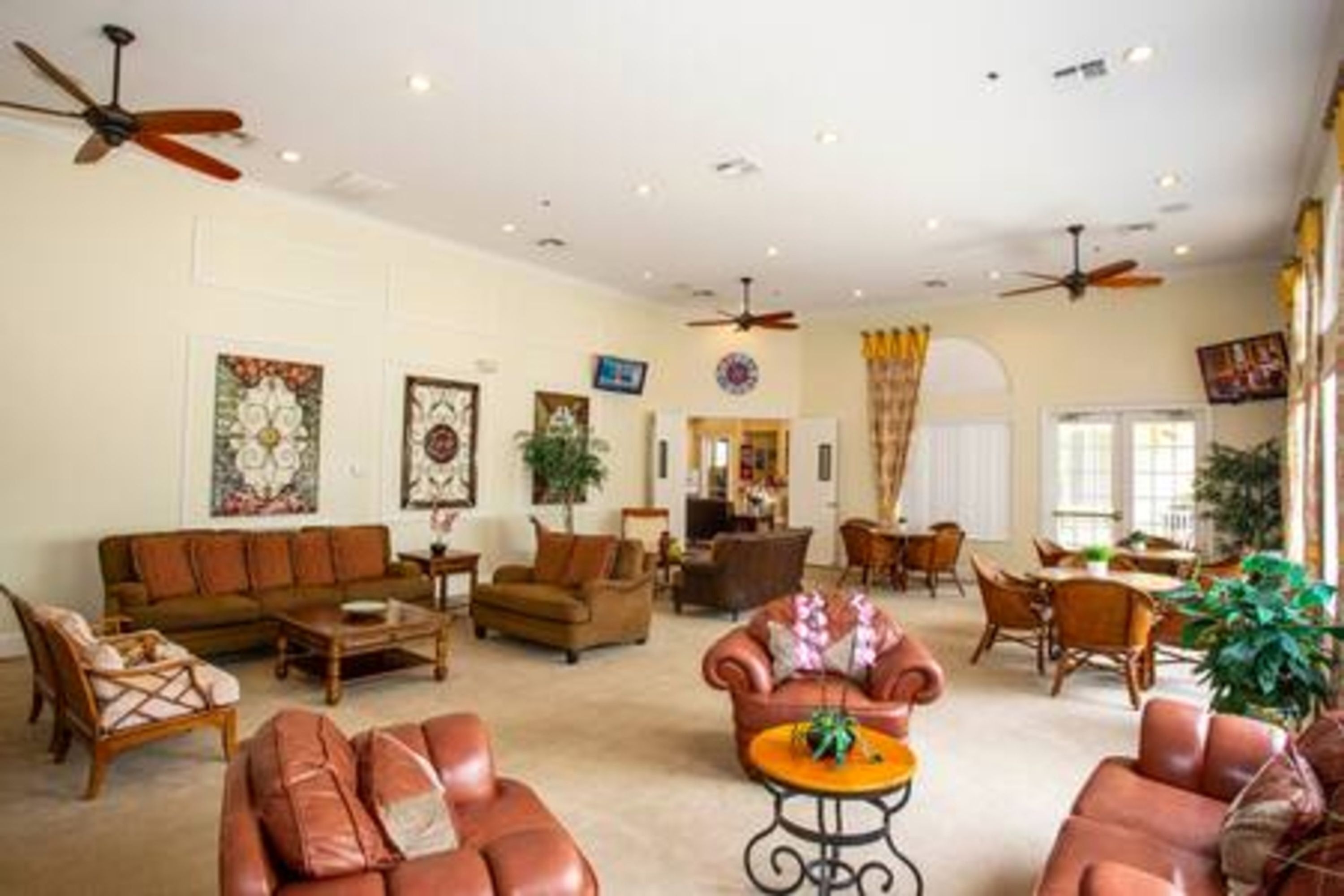 A spacious living room with a brown leather sofa, a coffee table, and a ceiling fan.