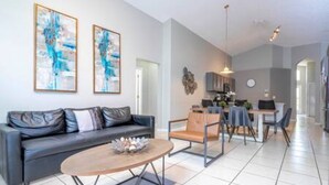 Un salon moderne avec un canapé, une table basse et des œuvres d’art accrochées au mur.