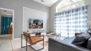 Un salon moderne avec un canapé, une table basse et un téléviseur fixé au mur.
