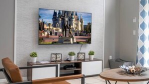 Un salon moderne doté d’un téléviseur à écran plat fixé sur un mur texturé, d’une table basse agrémentée d’objets décoratifs et d’un coin salon avec un fauteuil en cuir marron.
