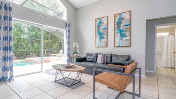 Un salon spacieux avec une grande fenêtre, un canapé, une table basse et une vue sur une piscine.