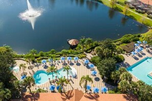 Een resort met een zwembad, een waterfontein en een zonneterras met parasols.
