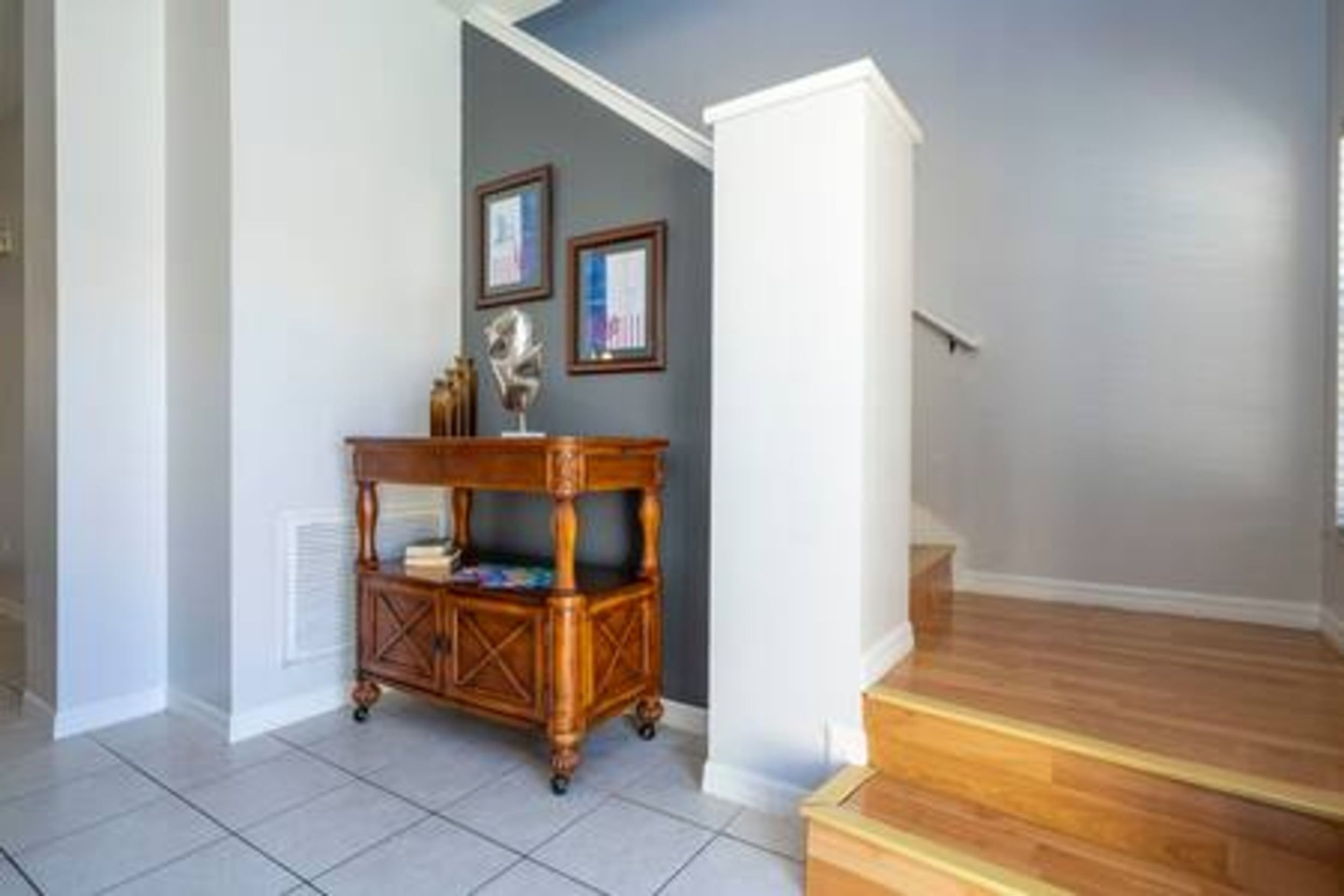 A hallway with a wooden floor, a small wooden table with a decorative item, and a staircase leading to another level.