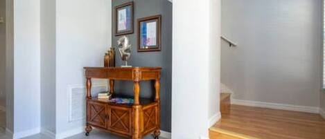 A hallway with a wooden floor, a small wooden table with a decorative item, and a staircase leading to another level.