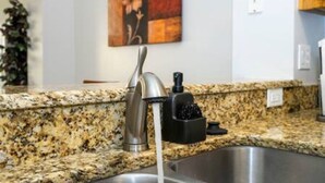 A kitchen with a granite countertop, stainless steel sink, and a faucet. - Cozy 3 BR w Private Pool (Kissimmee)
