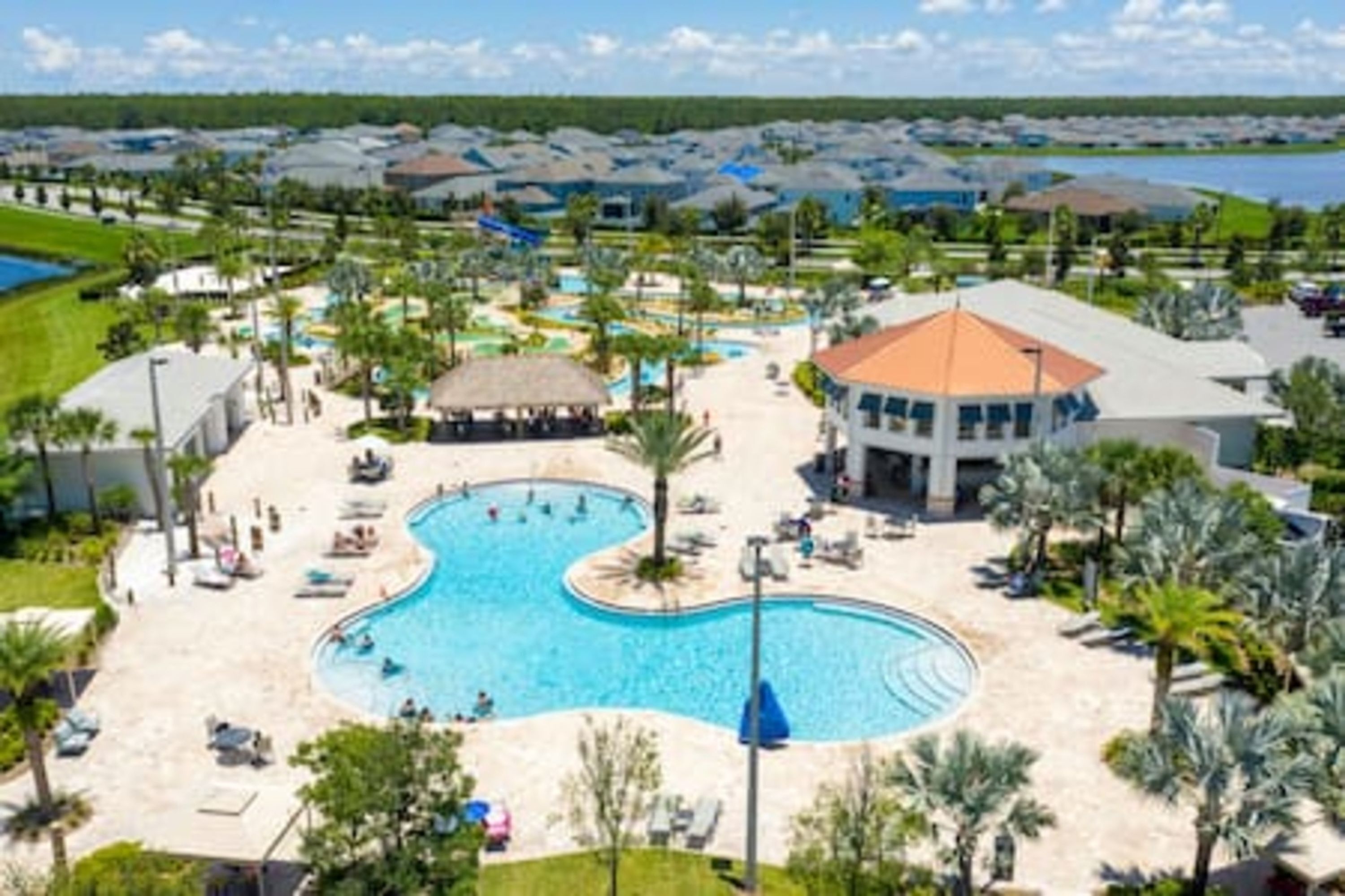 A resort with a central swimming pool, multiple buildings, and a view of the surrounding area.