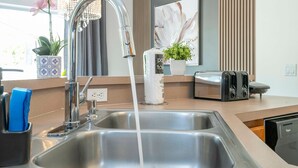 A modern kitchen with a stainless steel sink, a faucet, a toaster, and a potted plant. - 4 Bedrooms Close to Disney (Kissimmee)