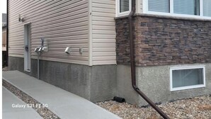 Een gebouw met horizontale beplating, een gevel van natuursteen en een raam met zonwering.