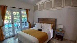 A hotel room with a bed, a nightstand, a ceiling fan, and a view of a pool through a glass door. - Cozy Margate Retreat Family Home With 2 Bedrooms (Margate)