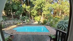 A pool surrounded by lush greenery and a wooden deck. - Cozy Margate Retreat Family Home With 2 Bedrooms (Margate)