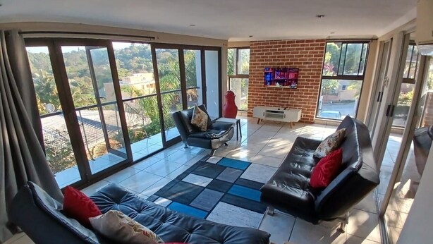 A spacious living room with large windows, a fireplace, and a modern sofa set. - Cozy Margate Retreat Family Home With 2 Bedrooms (Margate)