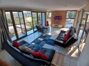 A spacious living room with large windows, a fireplace, and a modern sofa set. - Cozy Margate Retreat Family Home With 2 Bedrooms (Margate)