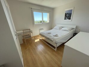 Ein Schlafzimmer mit Bett, Stuhl, Heizkörper, Fenster und einem Bild an der Wand.