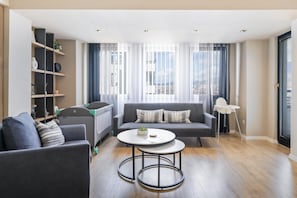 A modern living room with a sofa, a coffee table, and a bookshelf. - L&L Apartments - The Urban Loft Ohrid (Oher)