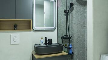 A modern bathroom with a built-in sink, mirror, and shower.