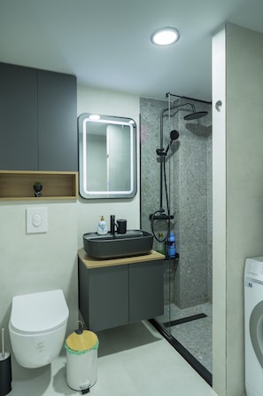 A modern bathroom with a built-in sink, mirror, and shower. - L&L Apartments - The Urban Loft Ohrid (Oher)