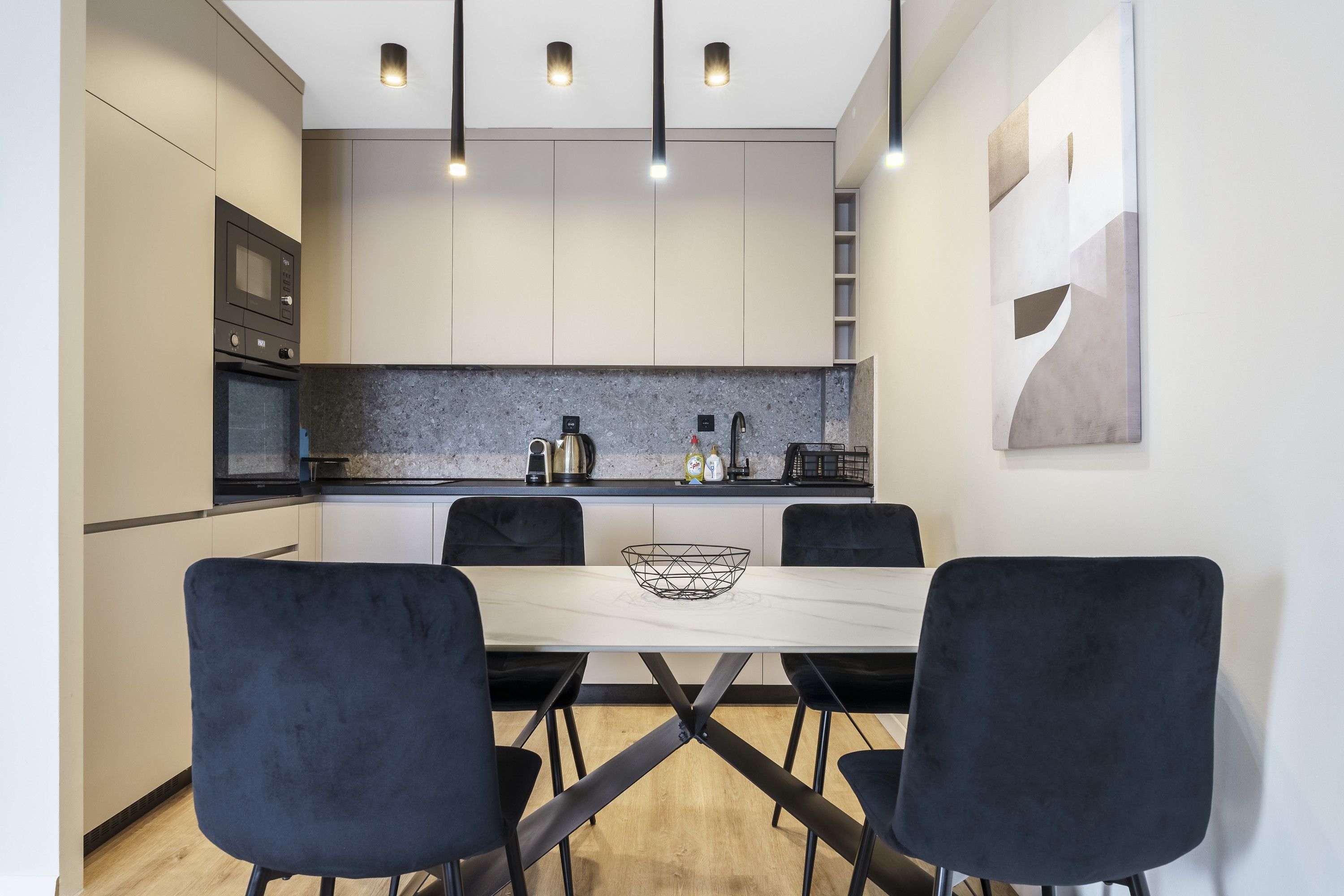 A modern kitchen with a dining table and chairs, built-in appliances, and pendant lighting.