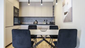 A modern kitchen with a dining table and chairs, built-in appliances, and pendant lighting.