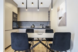 A modern kitchen with a dining table and chairs, built-in appliances, and pendant lighting. - L&L Apartments - The Urban Loft Ohrid (Oher)