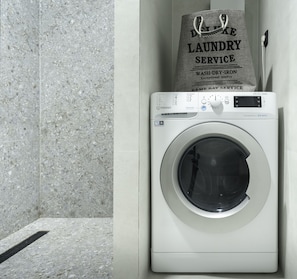 A front-loading washing machine with a control panel and a bag of laundry service on top.