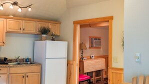 Une cuisine avec des meubles de rangement en bois, un réfrigérateur blanc et un ventilateur de plafond.