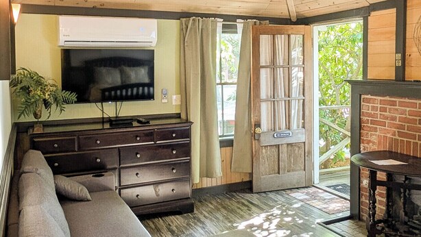 Ein modernes Wohnzimmer mit einem Ecksofa, einem Flachbildfernseher, einem Kamin und einer Holzbalkendecke.
