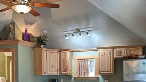 A kitchen with wooden cabinets, a stove, a refrigerator, and a ceiling fan. - Cabin surrounded by Lustrous Pine trees_Cabin 14 (Bar Harbor)