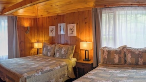 Une chambre confortable, aménagée dans le style d’un chalet, avec deux lits, des murs en bois et un plafond en pente.