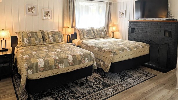 A bedroom with two beds, a fireplace, and a television.
