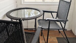 A small outdoor seating area with a round glass table and two wicker chairs. - New Cabin to ENJOY!_Cabin 20 (Bar Harbor)