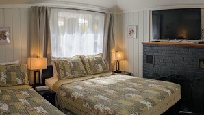 A cozy bedroom with two beds, a fireplace, and a television. - New Cabin to ENJOY!_Cabin 20 (Bar Harbor)