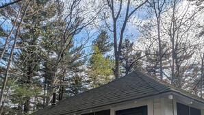 A small, single-story mobile home with a dark front door, numbered 20, and a screened porch. - New Cabin to ENJOY!_Cabin 20 (Bar Harbor)