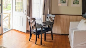 A wooden dining area with a table and chairs, a white couch, and a door leading outside.