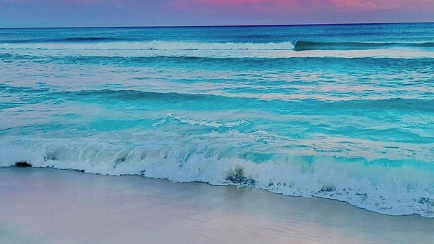 Una playa con olas y un cielo al atardecer.