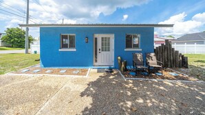 Una casita azul con una puerta blanca, dos ventanas y un porche con un banco.