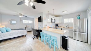 Una cocina moderna con una isla central, electrodomésticos de acero inoxidable y una zona de comedor con taburetes de bar.