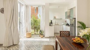 Una cucina moderna con mobili bianchi, un frigorifero in acciaio inossidabile e un'area pranzo con tavolo e sedie in legno.