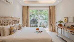 Ruime slaapkamer met een groot bed, een houten console en uitzicht op groen buiten het raam.