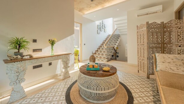 Een modern interieur met een ronde houten salontafel, een trap en een decoratieve wand.