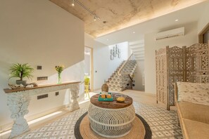 Un interior moderno con una mesa redonda de madera, una escalera y un panel decorativo.