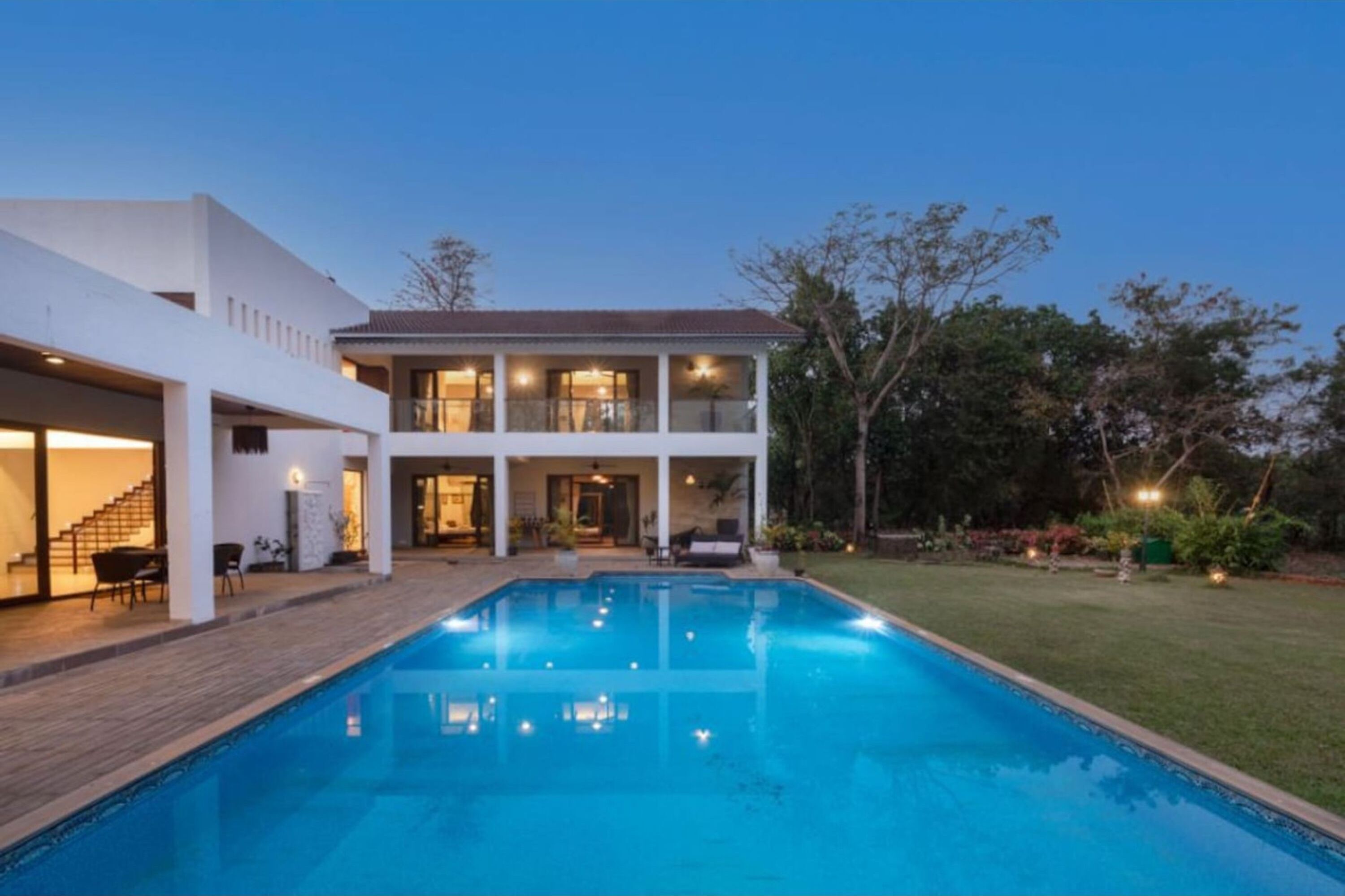 A modern two-story house with a swimming pool, a covered patio, and a well-maintained garden.