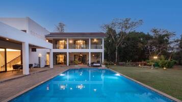 A modern two-story house with a swimming pool, a covered patio, and a well-maintained garden.