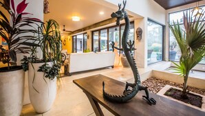 En lobby med en drageskulptur, store potteplanter og en receptionsdisk.