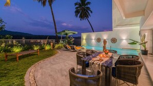 An outdoor patio area with a pool, wicker furniture, and a view of the hills. - Legacy by Hireavilla Natgeo Spot w Field Views (Siolim)