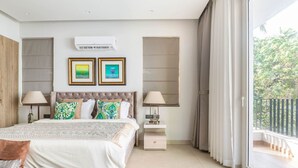 A bedroom with a large bed, two bedside tables, a nightstand, and a window with curtains. - Lux 5BR Villa in Anjuna Perfect for Groups Aria (Anjuna)