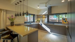 Une cuisine moderne dotée d’un îlot central, de luminaires suspendus et offrant une vue sur l’extérieur.