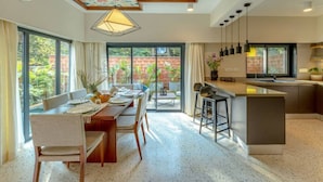 Une cuisine moderne dotée d’un îlot central, de grandes fenêtres et d’un coin repas avec une table et des chaises.